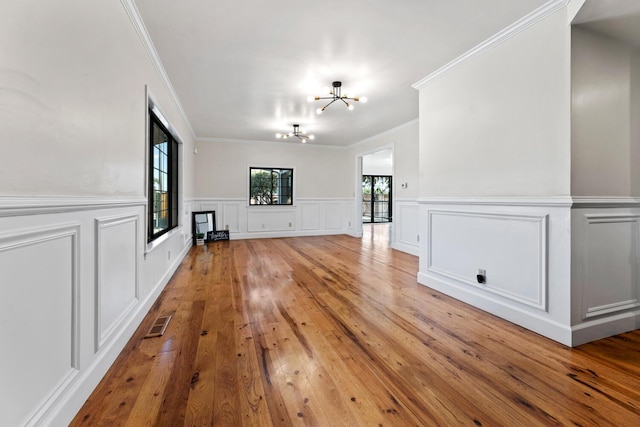 unfurnished living room with crown molding, a fireplace, light hardwood / wood-style flooring, and a notable chandelier