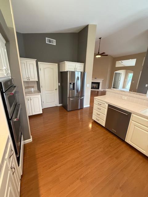 kitchen featuring tasteful backsplash, stainless steel appliances, white cabinets, dark hardwood / wood-style floors, and tile counters