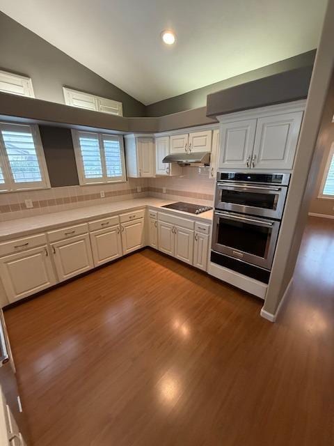 kitchen with black electric stovetop, vaulted ceiling, and white cabinetry