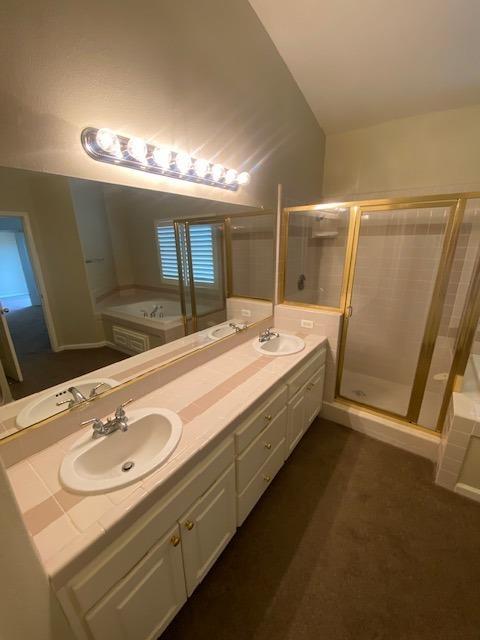 bathroom featuring vanity, vaulted ceiling, and independent shower and bath