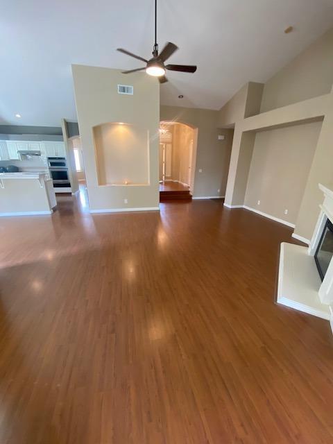 unfurnished living room with ceiling fan, lofted ceiling, and dark wood-type flooring