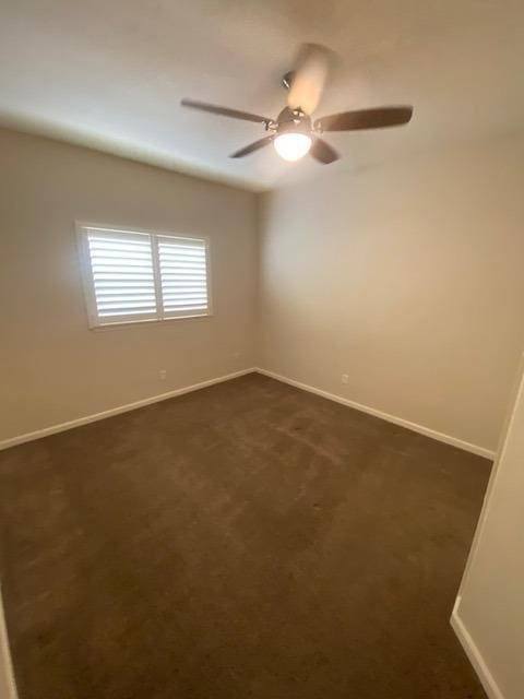 spare room with ceiling fan and dark carpet