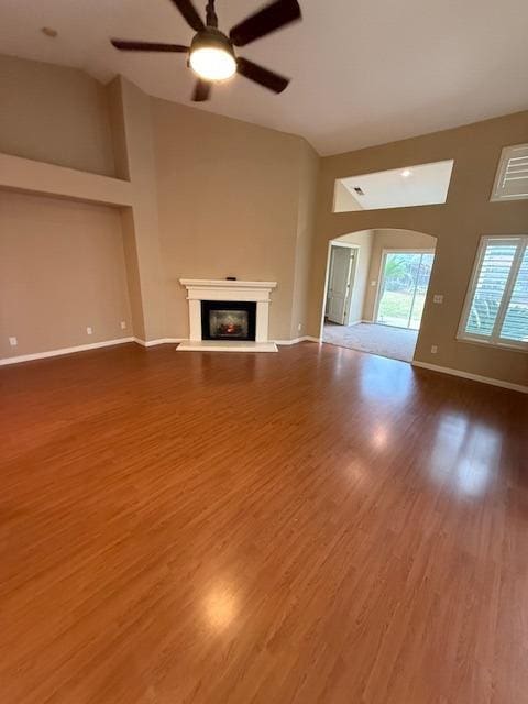 unfurnished living room with hardwood / wood-style floors, high vaulted ceiling, and ceiling fan