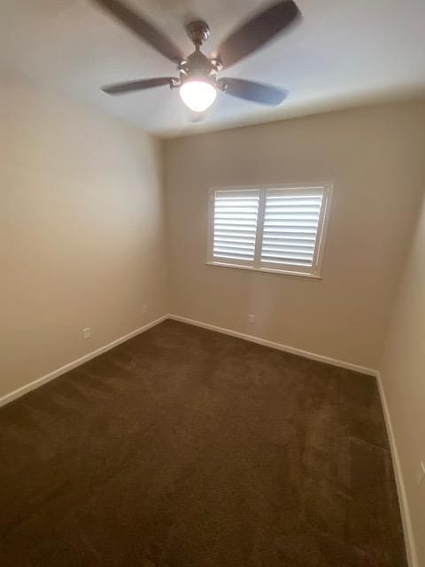 unfurnished room with dark carpet and ceiling fan