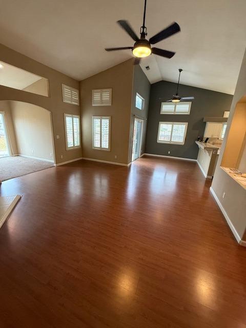 unfurnished living room with ceiling fan, dark hardwood / wood-style flooring, and high vaulted ceiling