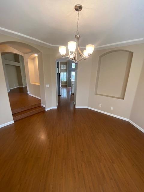 empty room with dark hardwood / wood-style flooring and an inviting chandelier