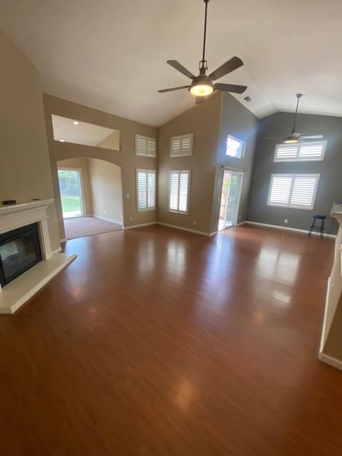 unfurnished living room with hardwood / wood-style flooring, vaulted ceiling, and ceiling fan