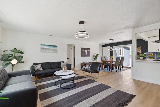 living room featuring a textured ceiling, a chandelier, and light hardwood / wood-style floors