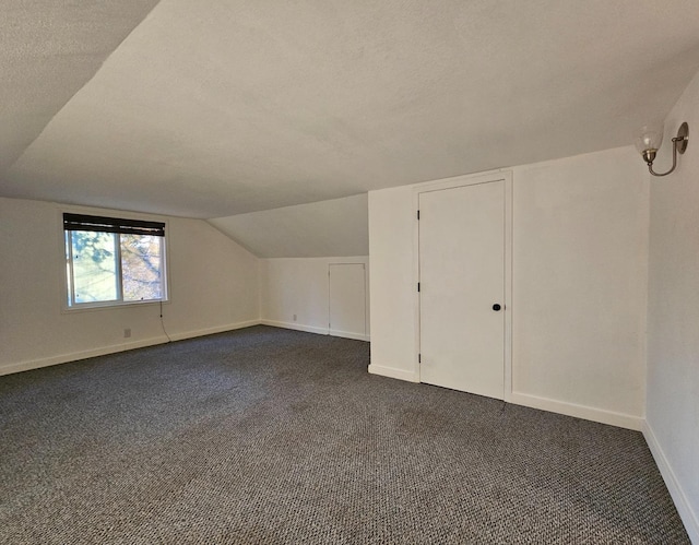 bonus room with lofted ceiling, a textured ceiling, and dark colored carpet