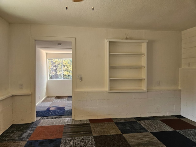 unfurnished room with ceiling fan and a textured ceiling