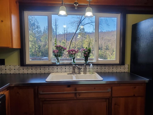 kitchen with pendant lighting, black refrigerator, and sink