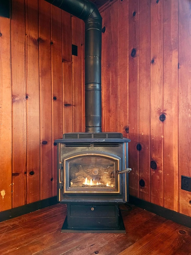 interior details with wood walls, a wood stove, and hardwood / wood-style flooring