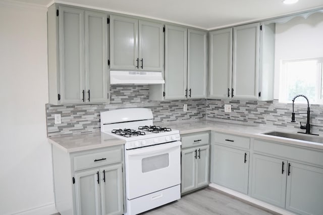 kitchen with sink, light hardwood / wood-style flooring, gray cabinetry, tasteful backsplash, and white range with gas cooktop