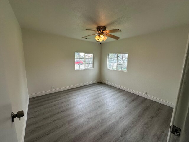 unfurnished room with dark wood-type flooring, a textured ceiling, and ceiling fan