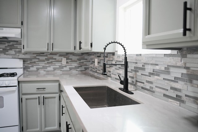 kitchen featuring sink, white range with gas stovetop, and backsplash