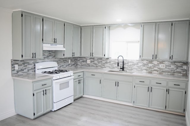 kitchen featuring tasteful backsplash, white range with gas cooktop, sink, and gray cabinetry