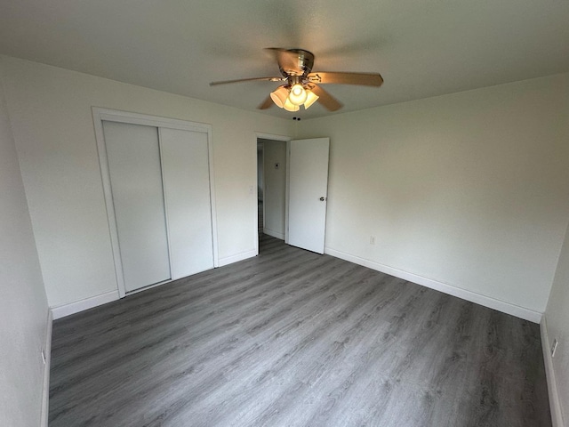 unfurnished bedroom with ceiling fan, wood-type flooring, and a closet