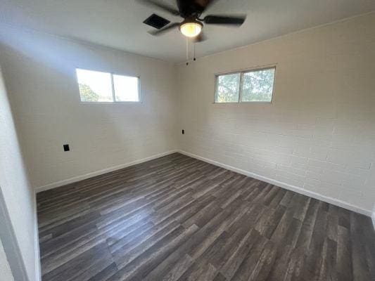 unfurnished room with a wealth of natural light, ceiling fan, and dark wood-type flooring