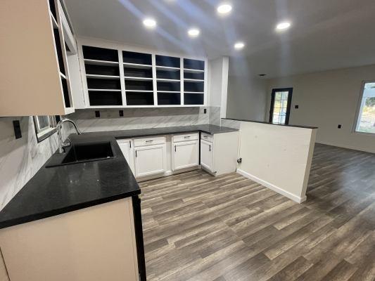 kitchen featuring white cabinets, sink, kitchen peninsula, backsplash, and dark hardwood / wood-style flooring