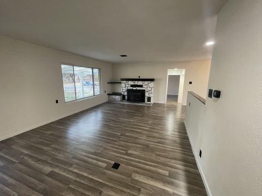 unfurnished living room featuring a stone fireplace and dark hardwood / wood-style flooring