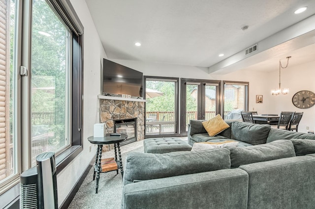 living room featuring a notable chandelier, carpet floors, a fireplace, and french doors