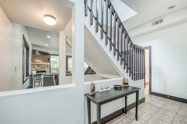 staircase featuring a skylight, a fireplace, and tile patterned flooring