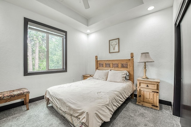 carpeted bedroom featuring a closet, ceiling fan, and a raised ceiling