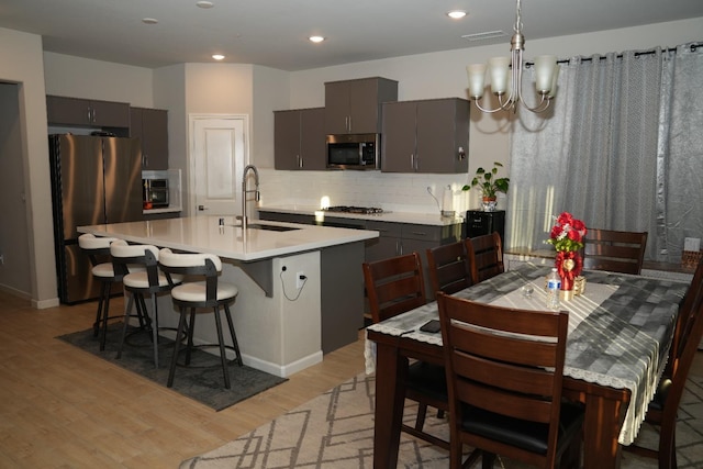 kitchen featuring appliances with stainless steel finishes, light hardwood / wood-style floors, backsplash, a breakfast bar area, and gray cabinets