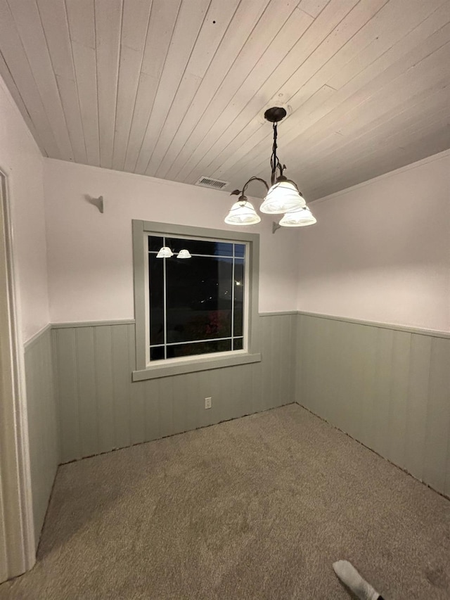 empty room featuring wood walls, wood ceiling, and carpet