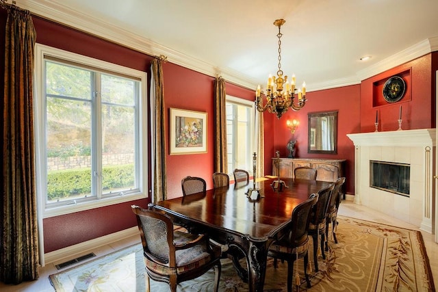 dining room with ornamental molding, a notable chandelier, a wealth of natural light, and a tile fireplace