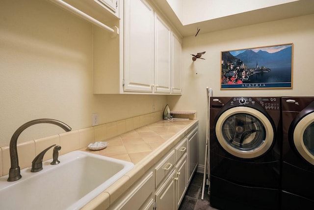 washroom featuring dark tile patterned floors, washer and clothes dryer, sink, and cabinets