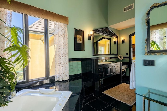 bathroom featuring tiled tub, plenty of natural light, tile patterned floors, and vanity