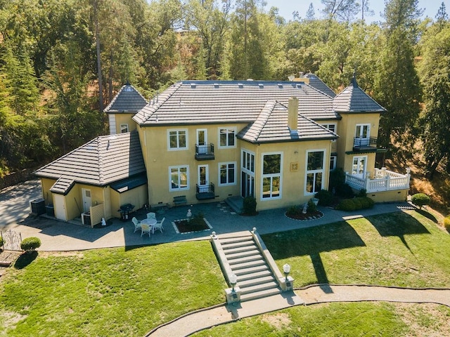 rear view of house featuring a patio, a lawn, and central AC unit