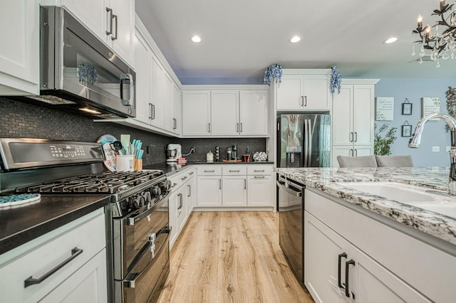 kitchen featuring appliances with stainless steel finishes, sink, light hardwood / wood-style flooring, and white cabinets