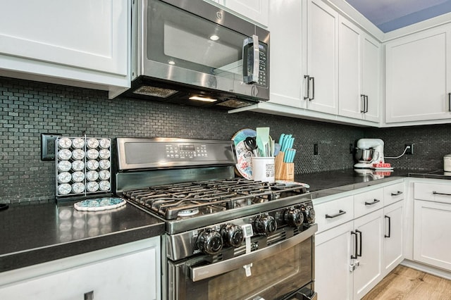 kitchen featuring stainless steel appliances, white cabinets, tasteful backsplash, and light wood-type flooring