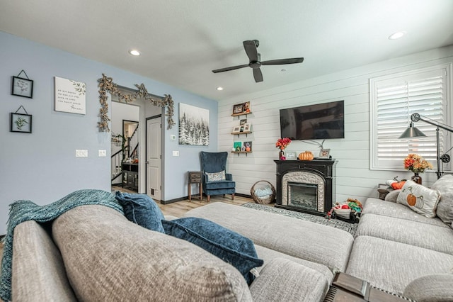 living room featuring ceiling fan, wood walls, and light hardwood / wood-style flooring