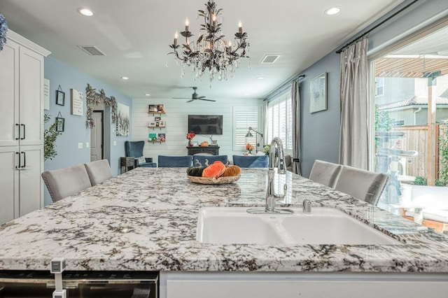 dining space featuring ceiling fan with notable chandelier and sink