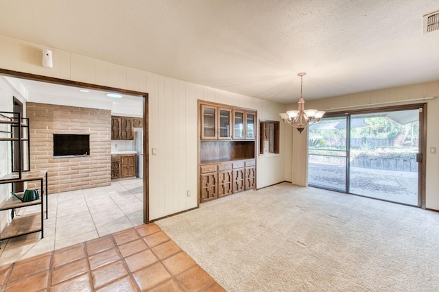 unfurnished dining area with light colored carpet, an inviting chandelier, and a textured ceiling