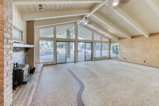 unfurnished living room with vaulted ceiling with beams, plenty of natural light, carpet flooring, and a wood stove