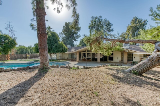 rear view of property with a fenced in pool and a patio area