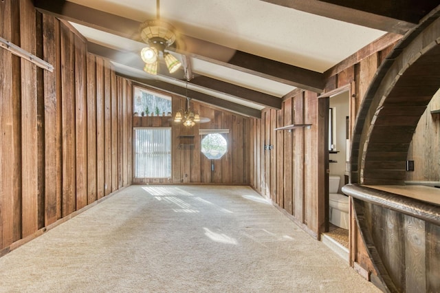 interior space featuring light colored carpet, lofted ceiling with beams, and wooden walls