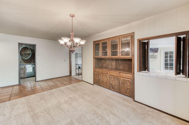 unfurnished dining area featuring light colored carpet and a notable chandelier