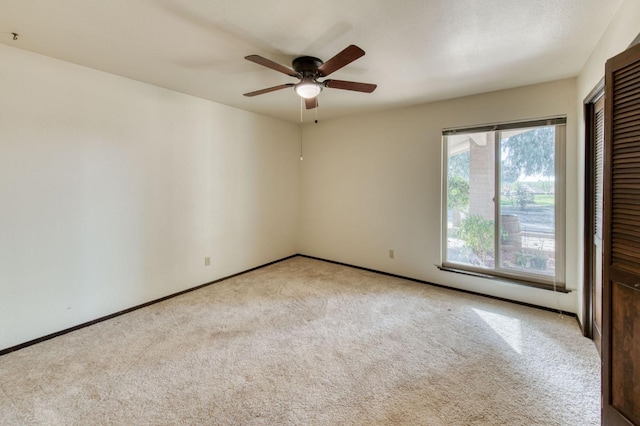 carpeted spare room featuring ceiling fan