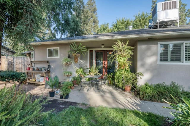 back of property with central AC and a patio