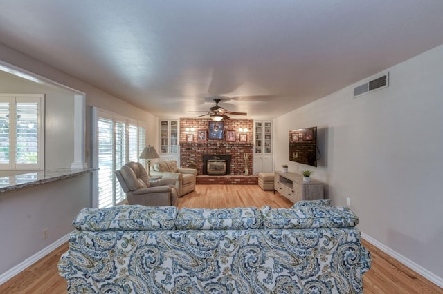 living room with light hardwood / wood-style floors, built in features, and ceiling fan