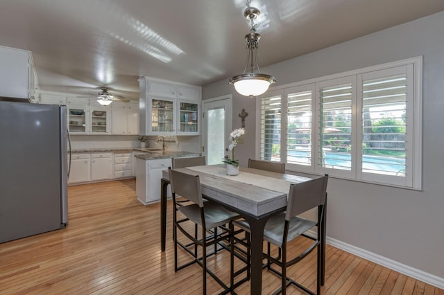 dining room featuring ceiling fan, sink, and light wood-type flooring