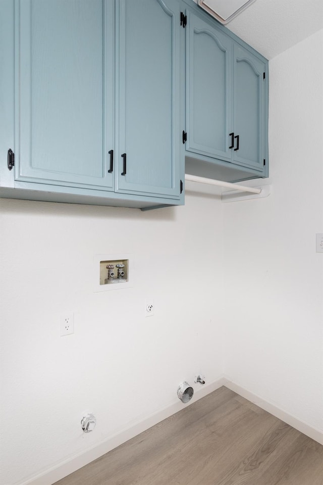 laundry area with hookup for a gas dryer, washer hookup, hookup for an electric dryer, light wood-type flooring, and cabinets