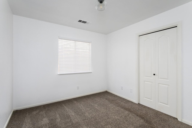 unfurnished bedroom featuring a closet and dark carpet