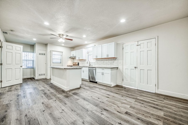 kitchen featuring a center island, white cabinetry, stainless steel dishwasher, and light hardwood / wood-style flooring