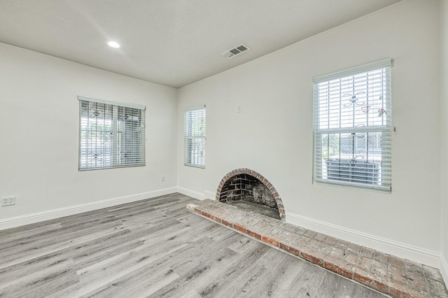 unfurnished living room featuring a brick fireplace and light hardwood / wood-style flooring